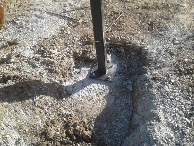 Close-up of a steel post on a base plate set into a concrete footing