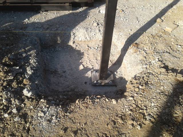 Steel column base bolted down on a fresh concrete footing