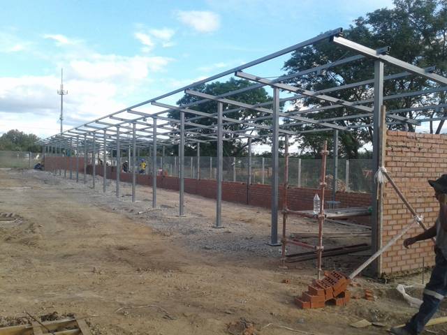 Long galvanised steel carport frame over a new brick wall