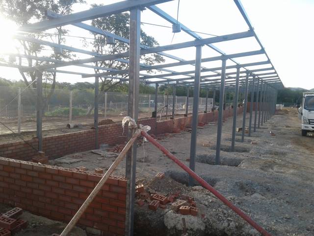 Carport frame braced during installation next to brickwork