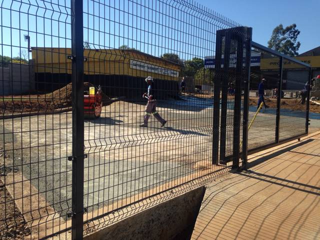 Green mesh panels and a swing gate being installed at a commercial site