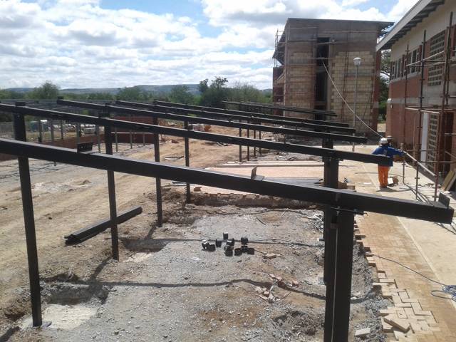 Steel walkway beams on posts beside a building under construction